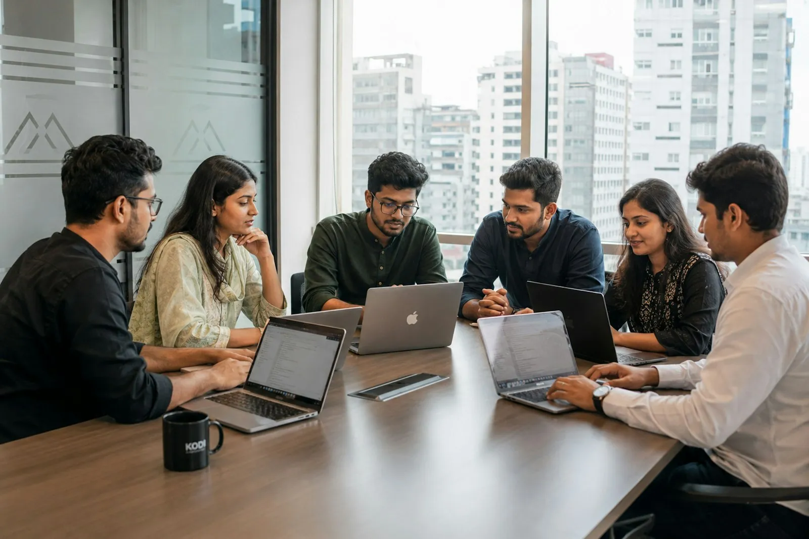 The team at work on laptops around a shared wooden table